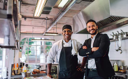 cook and manager smiling in restaurant kitchen