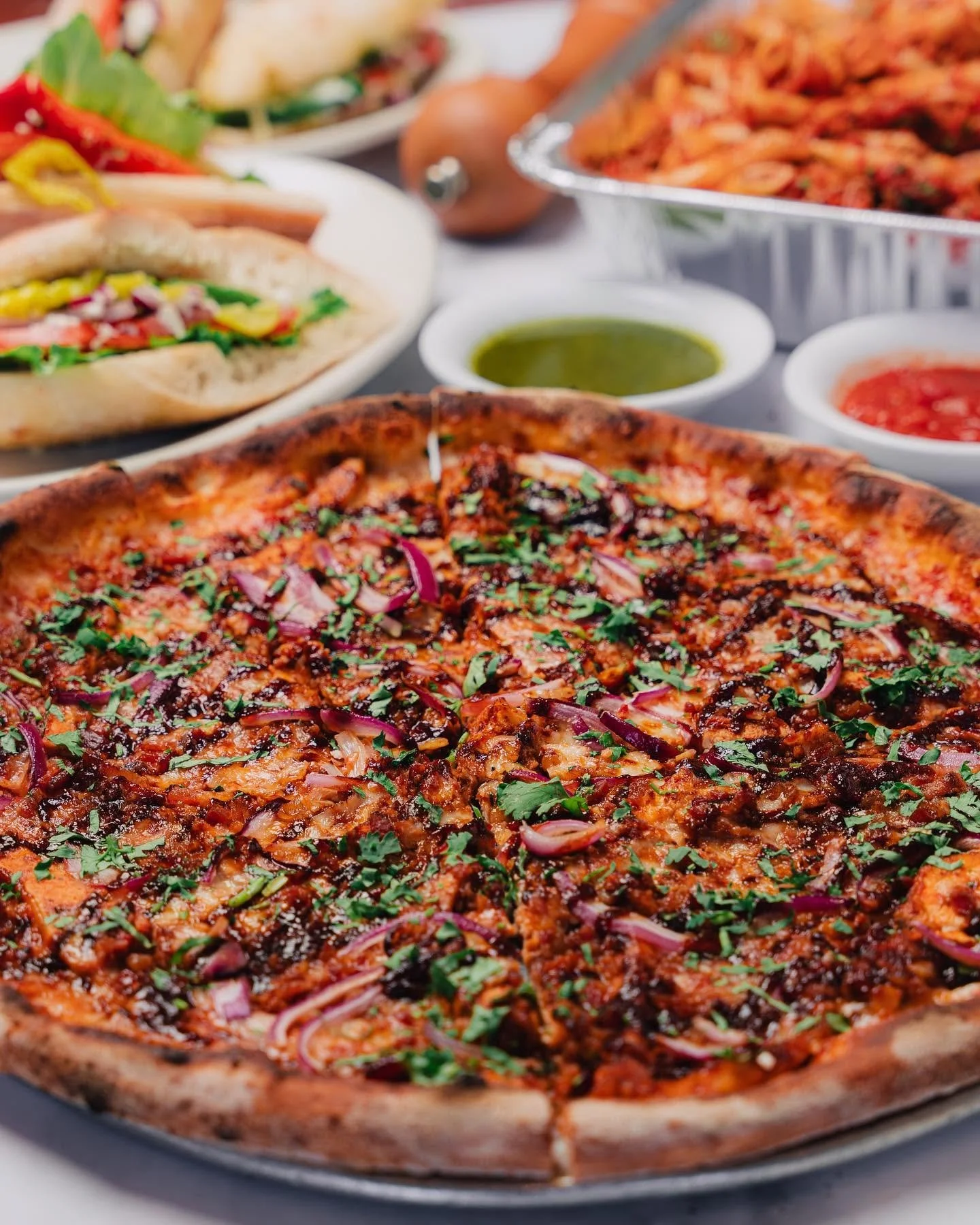 Close-up of a freshly baked Amici's specialty pizza topped with red onions and herbs.