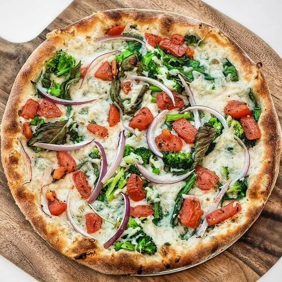 Amici’s Asante vegan pizza with Daiya vegan cheese, baby spinach, broccoli, red onions, tomatoes, and fresh basil.