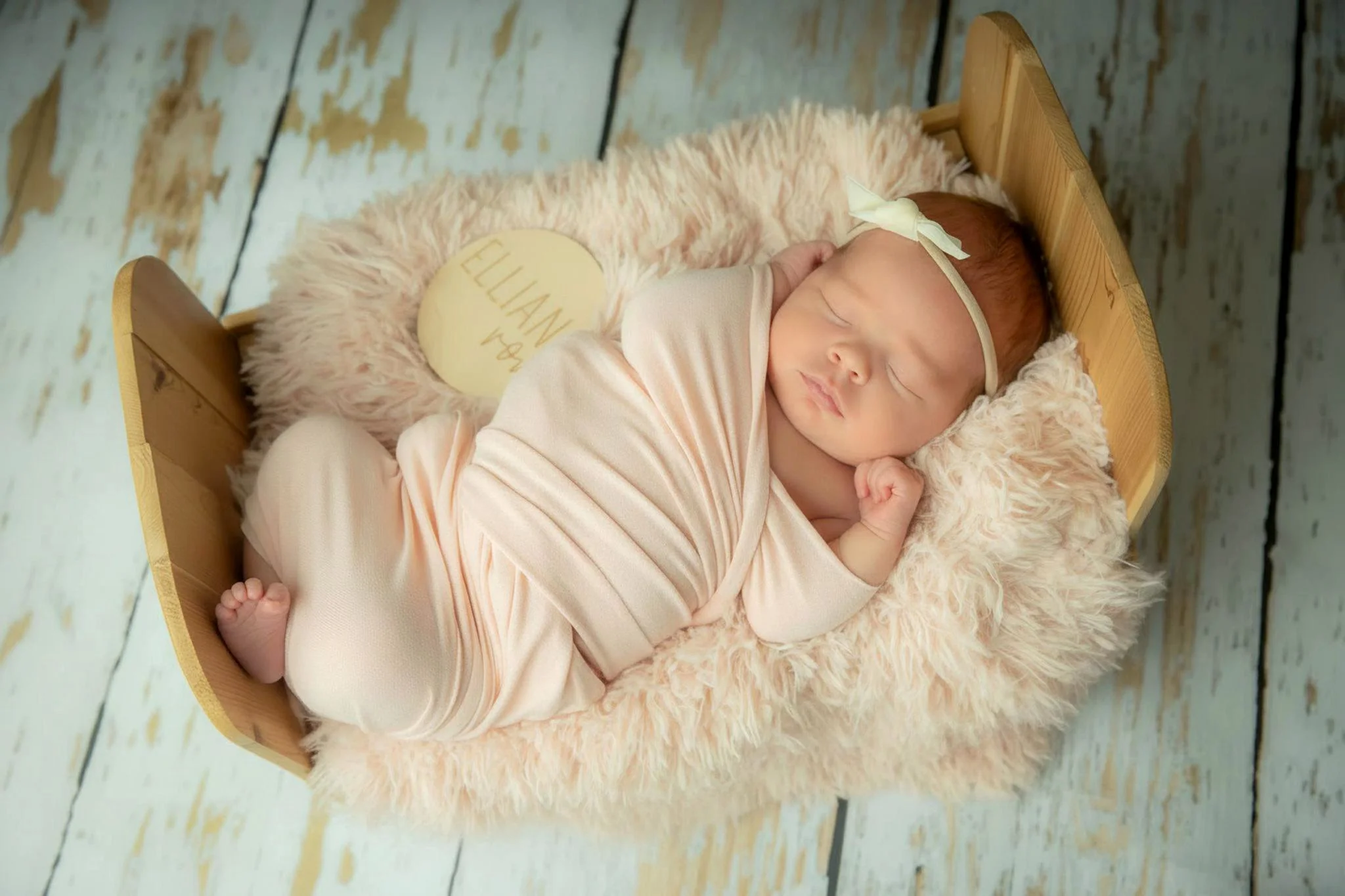 Omaha Newborn Photographer baby girl wrapped in pink on a furry pink bed in studio 