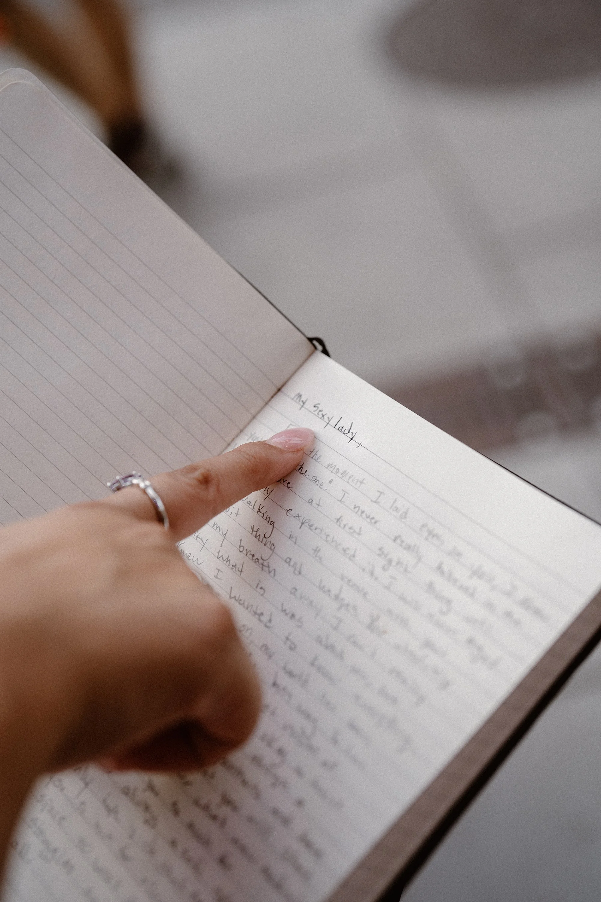 A bride's perfectly manicured hand traces the handwriting of her vows.