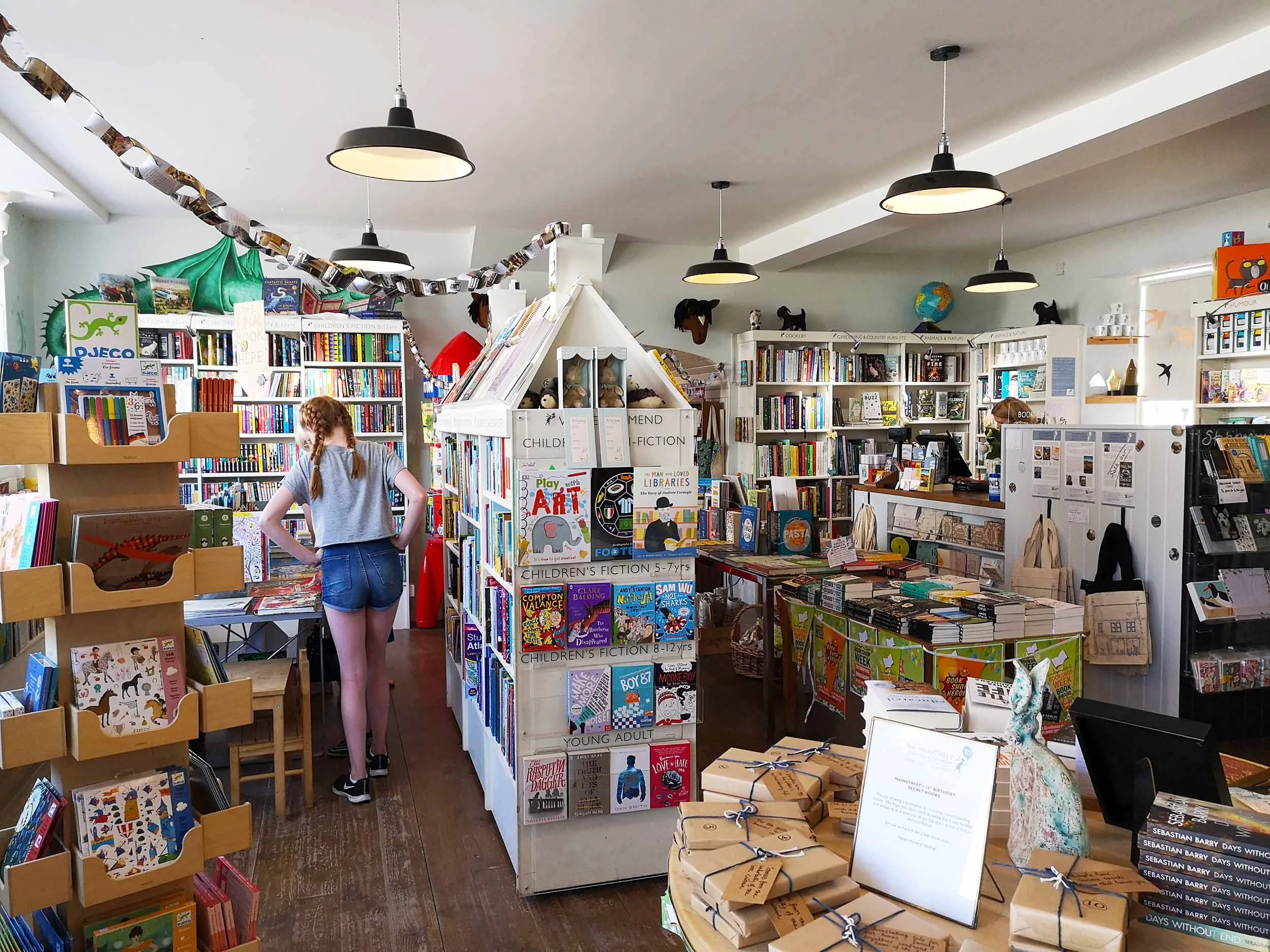 Children’s section to the left, cookery and nature to right near the till. Secret 10th birthday books are wrapped and piled on the table by the door.