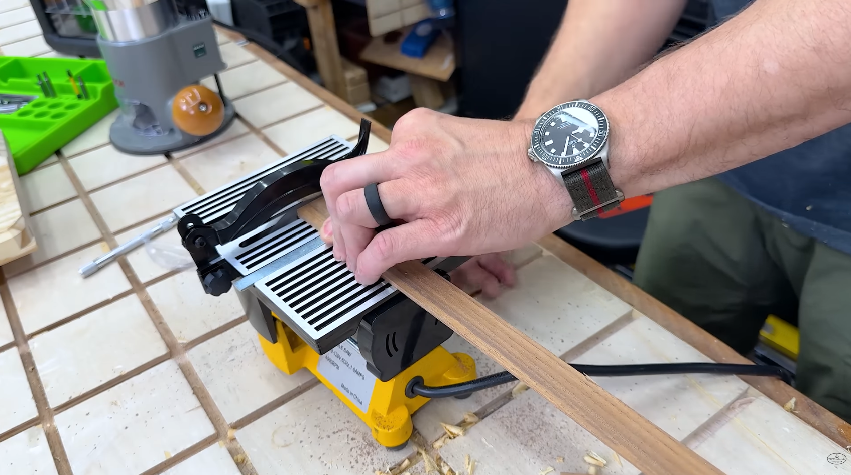 mini table saw cutting a small piece of wood on a workbench