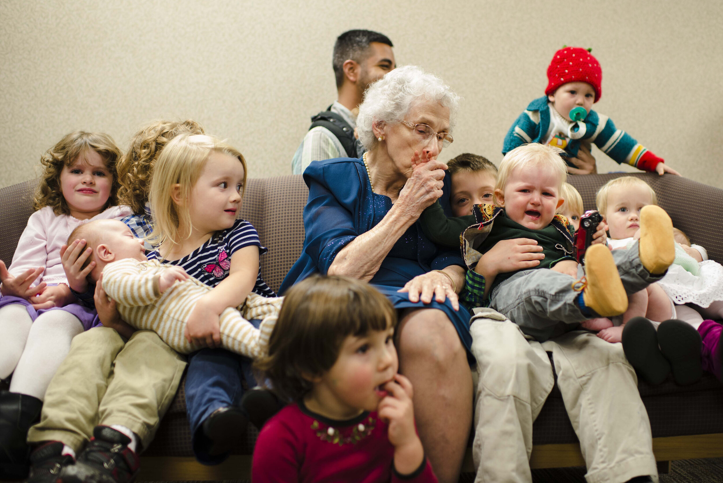  Polly Brown gathers with her great grandchildren on New Comer’s funeral parlor sofa October 29, 2017 in Rochester, NY. Her husband, Ralph Brown, had recently passed and his family gathered for his funeral.  