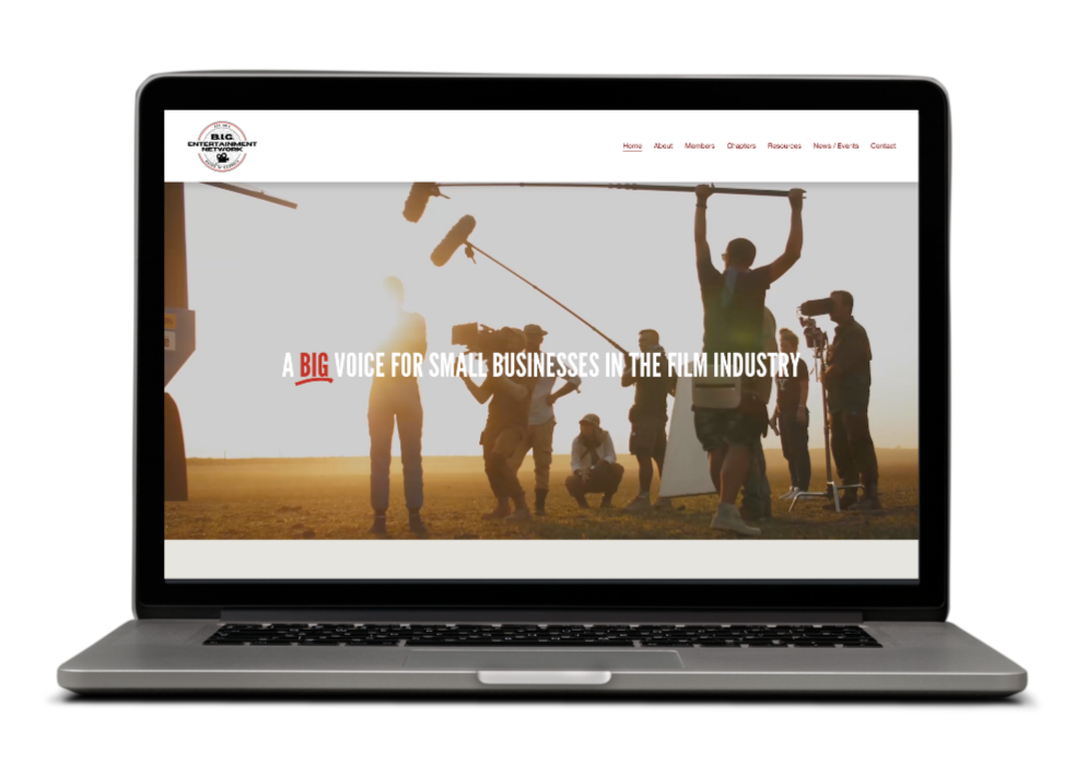 Laptop screen displaying a film industry website with a background of filmmakers and crew working outdoors at sunset.