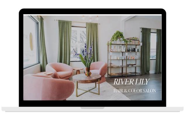 Laptop screen displaying interior of a boutique with pink chairs, green curtains, a wooden table with a vase of flowers, and a gold bookcase.