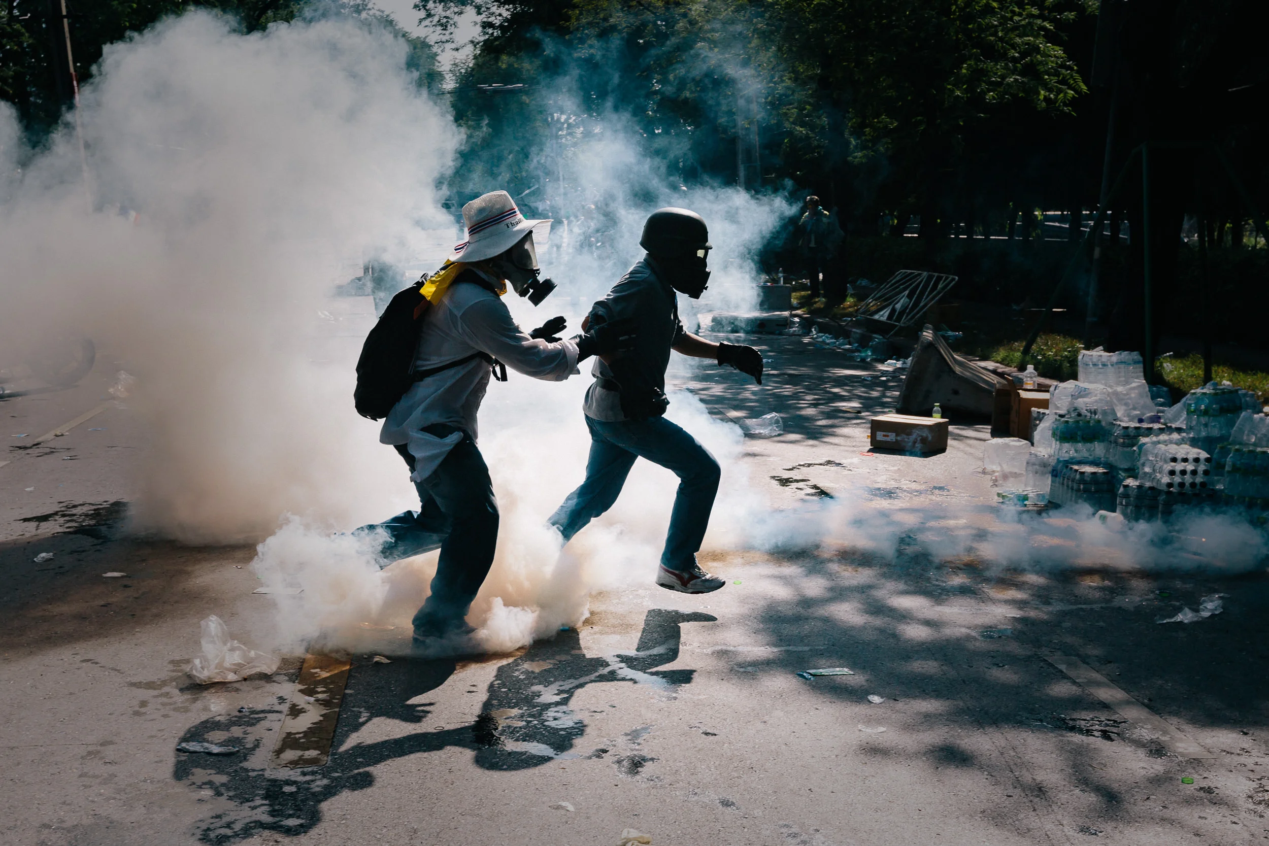 A protester kicks a tear gas canister back towards police lines during a stand-off between anti-Government protesters and police at Government House in Bangkok.