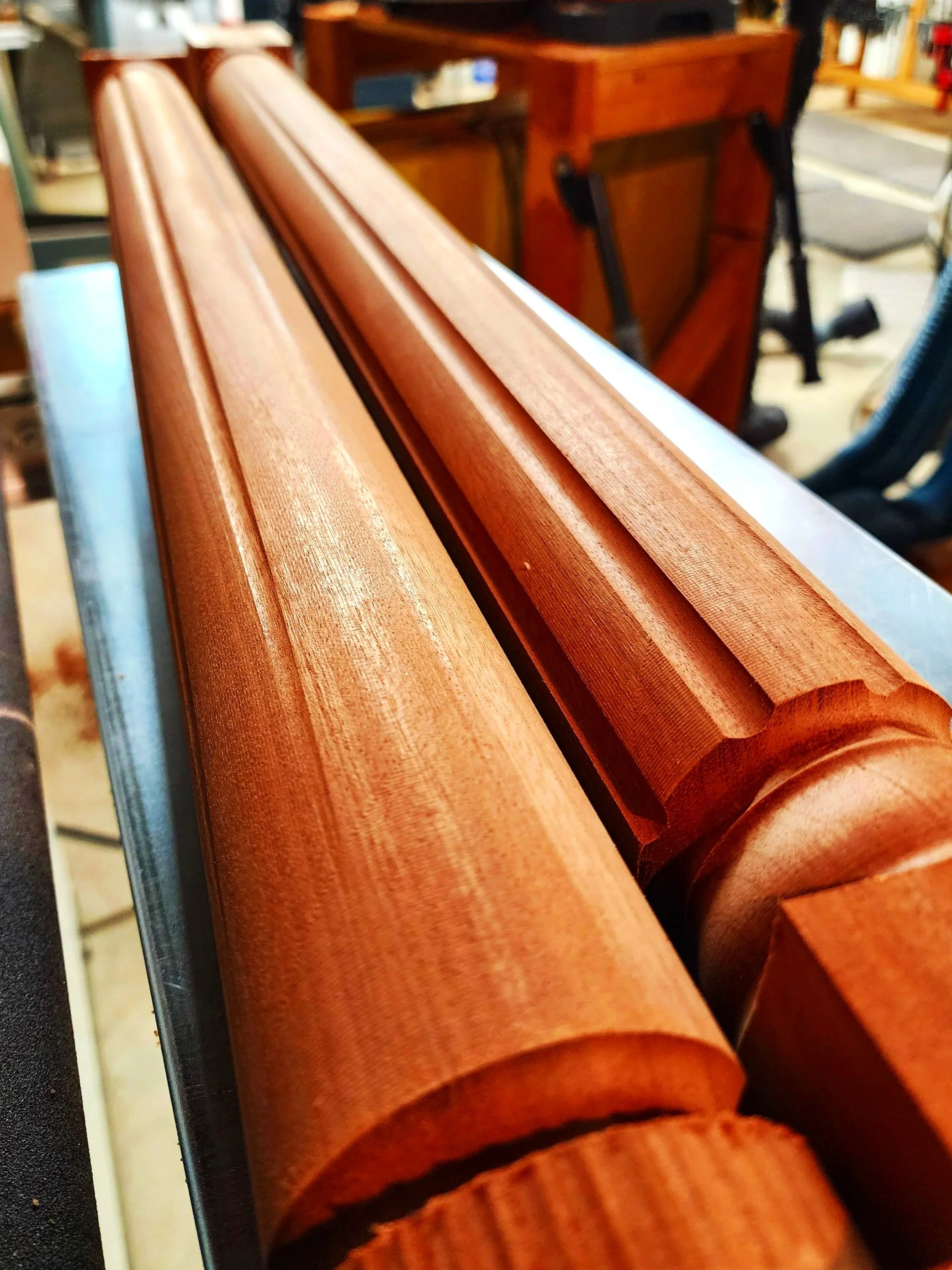 Close-up of a polished wooden chair armrest with a rounded edge, showing a smooth finish and visible wood grain.