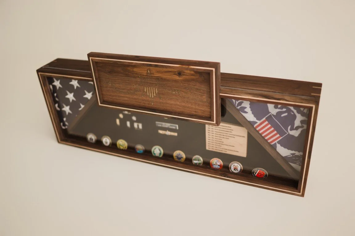 Decorative display case with military insignias, an American flag motif, and various badges.