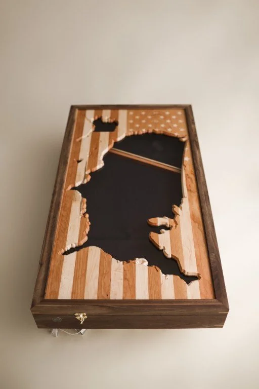 A wooden cornhole game board with a cutout shape of the state of Florida, painted black, in the middle.