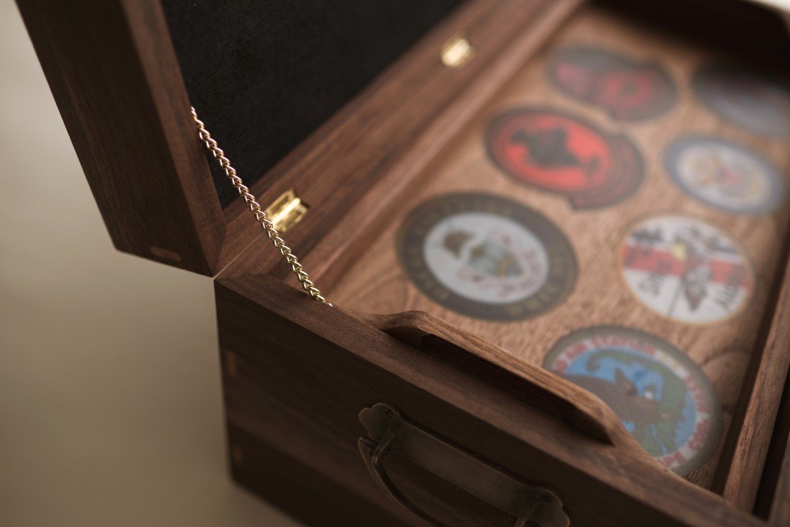 An open wooden box containing several military challenge coins with various designs and emblems.