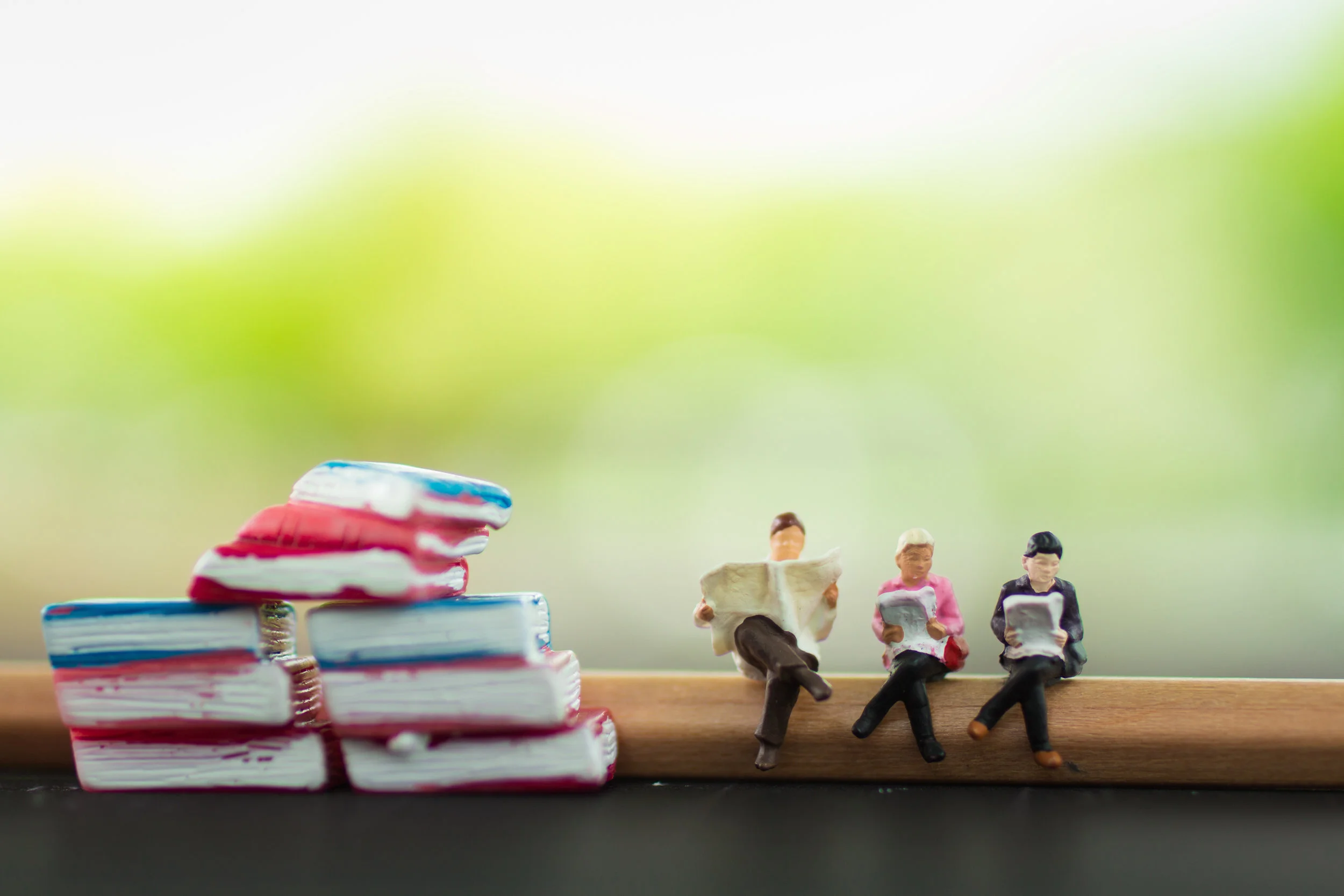 Miniature people read book stand beside the book stack using as background education or business concept