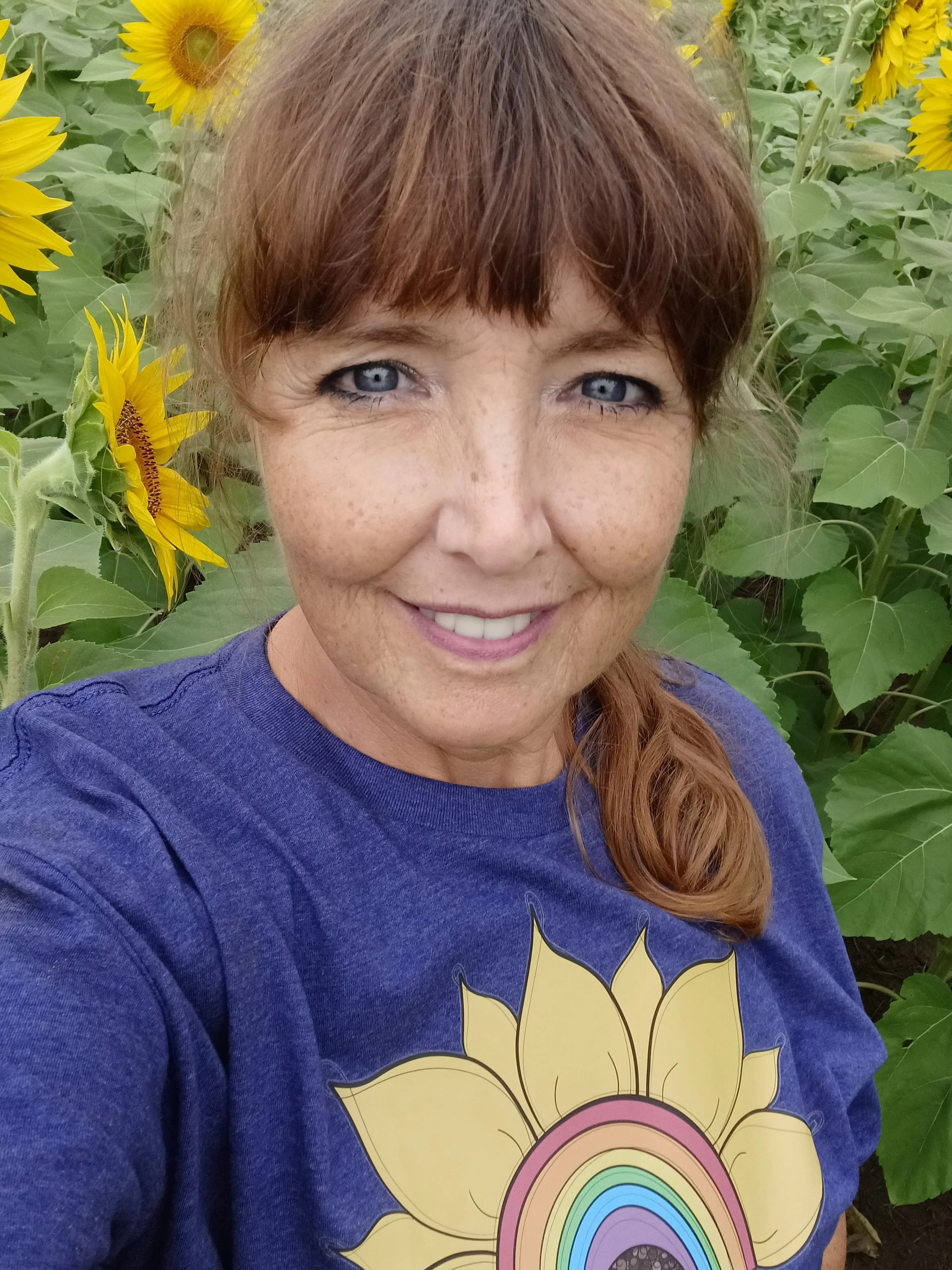 A woman with curly red hair and glasses, smiling at the camera.