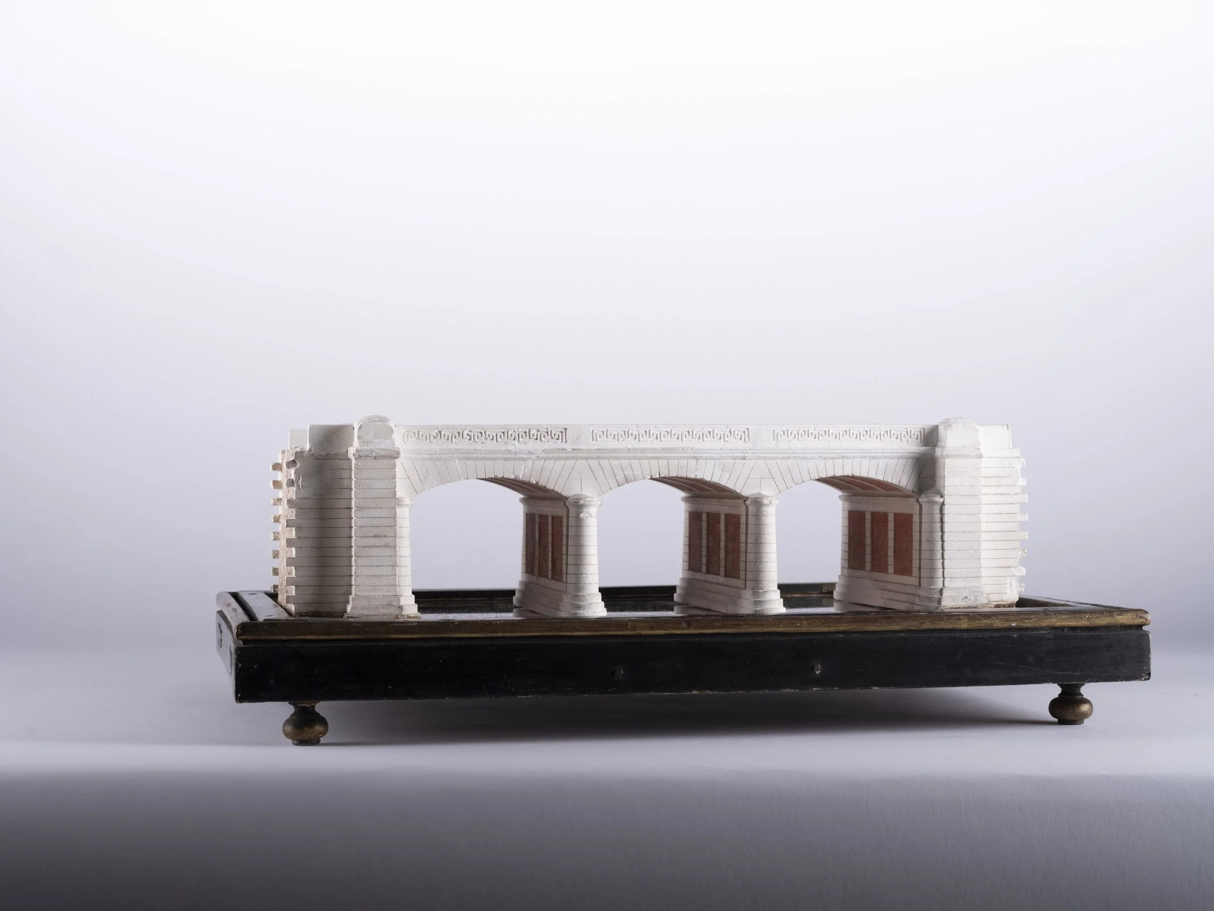 Maquette ancienne d’un pont de Brunoy à arches, en matériaux clairs avec détails rouges, posée sur un socle sombre. L’objet évoque une reconstitution architecturale ou pédagogique d’un ouvrage patrimonial.