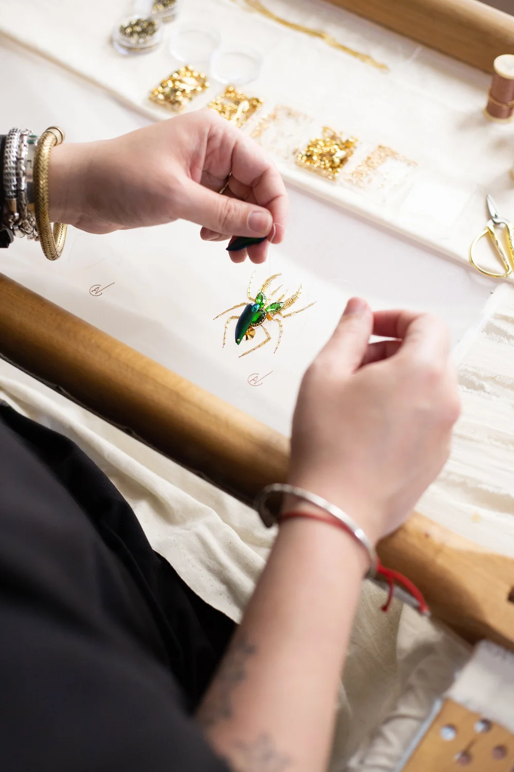l'artisan atelier noboru en train de broder avec des pierres semi précieuse sur de l'organza de soie