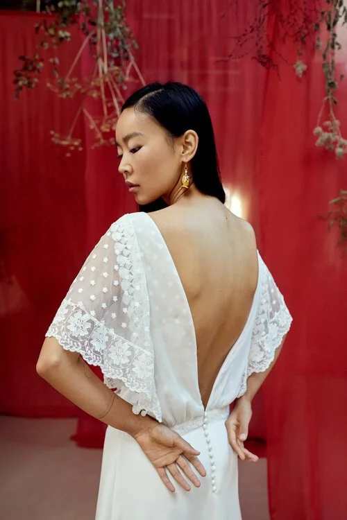 une robe de mariée avec un décolleté plongeant dans le dos et manches chauve souris, fabrication française