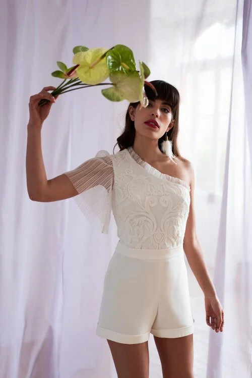 une tenue de mariage civil avec un short et un haut à manche asymétrique en dentelle