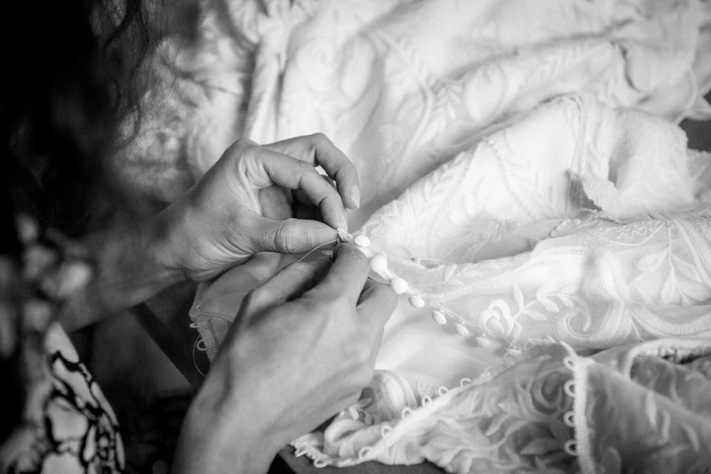créatrice de robe de mariée de l'atelier salomé gautard en train de coudre des petits boutons de soie