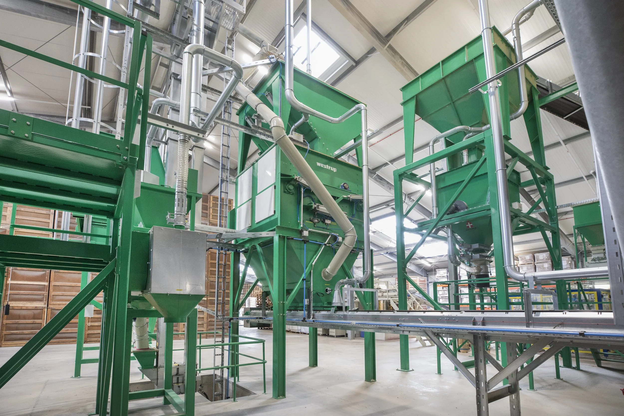 Industrial equipment in a factory with green machinery and metal pipes.