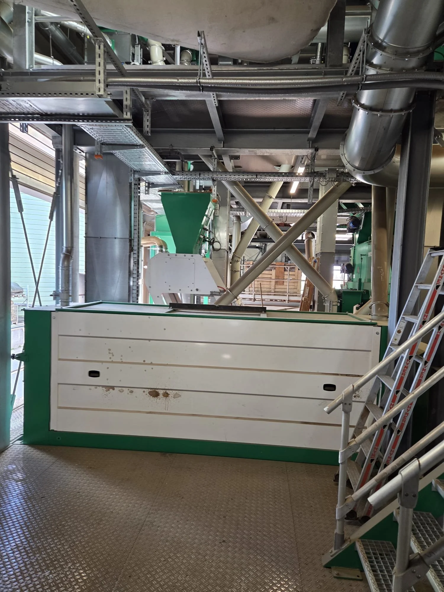 Industrial machinery with pipes, ducts, and metal framework, likely a processing or manufacturing plant.