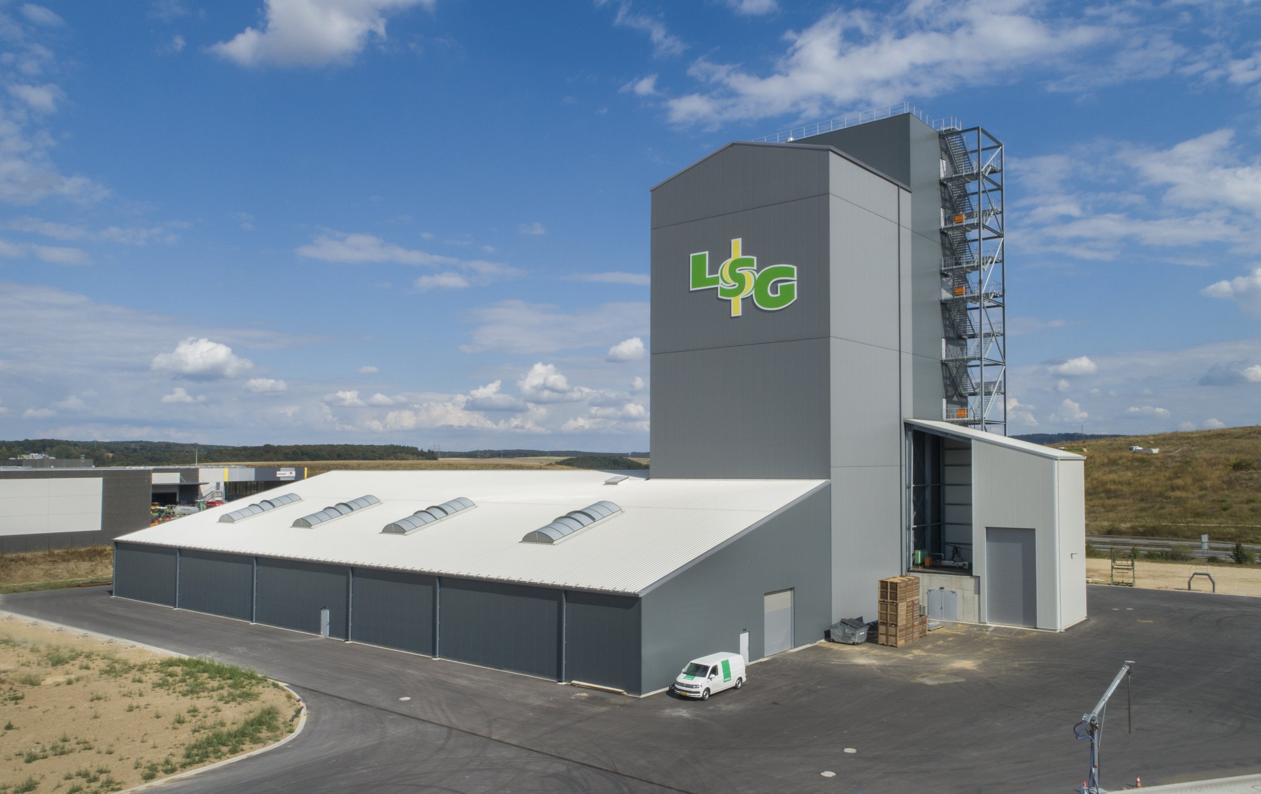 Industrial building with the logo 'LSG' on the front, under a partly cloudy sky.