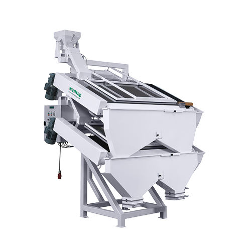 Grande machine industrielle blanche équipée d'un tapis roulant incliné et d'un panneau de commande, utilisée pour le traitement ou le tri de matériaux.