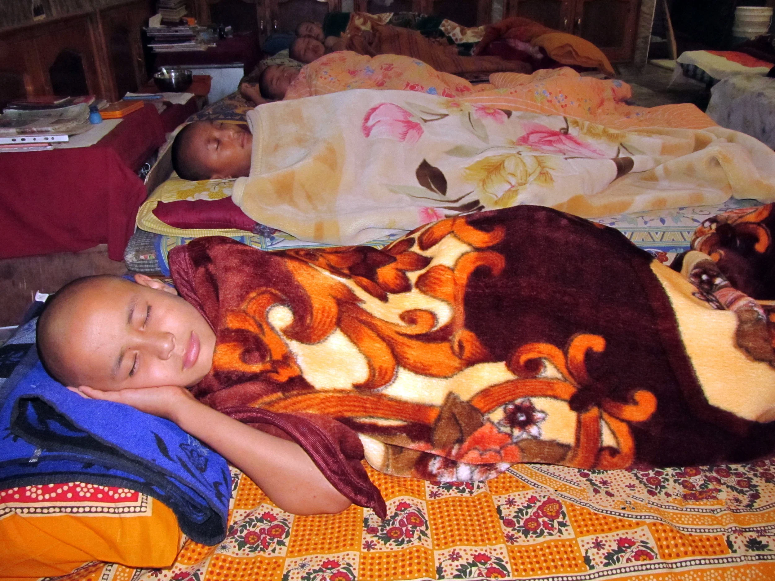 Young monks sleeping in the temporary quarters during winter while waiting for the completion of their hostels.