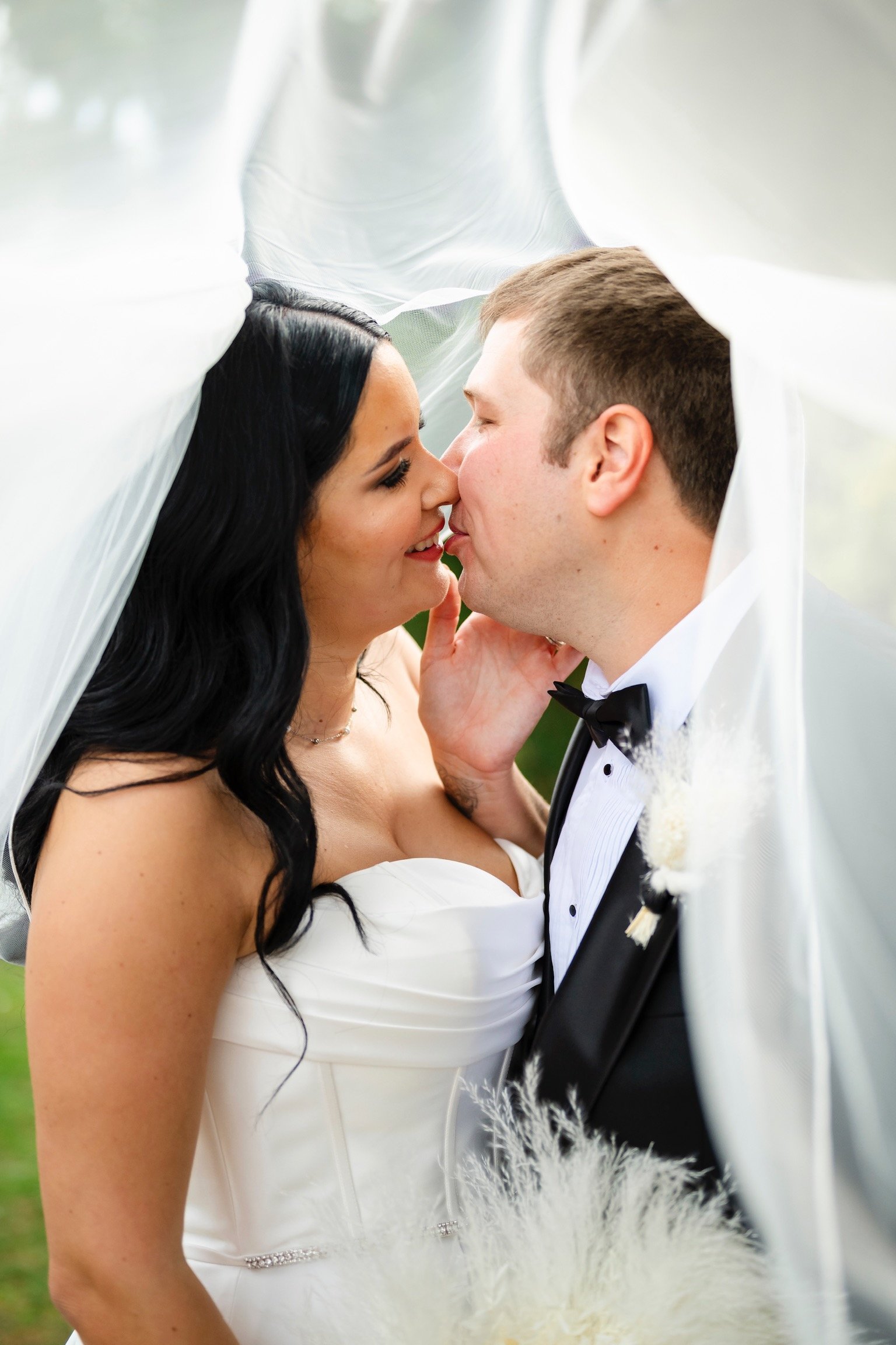 A bride and groom sharing an intimate moment under her veil on their wedding day.