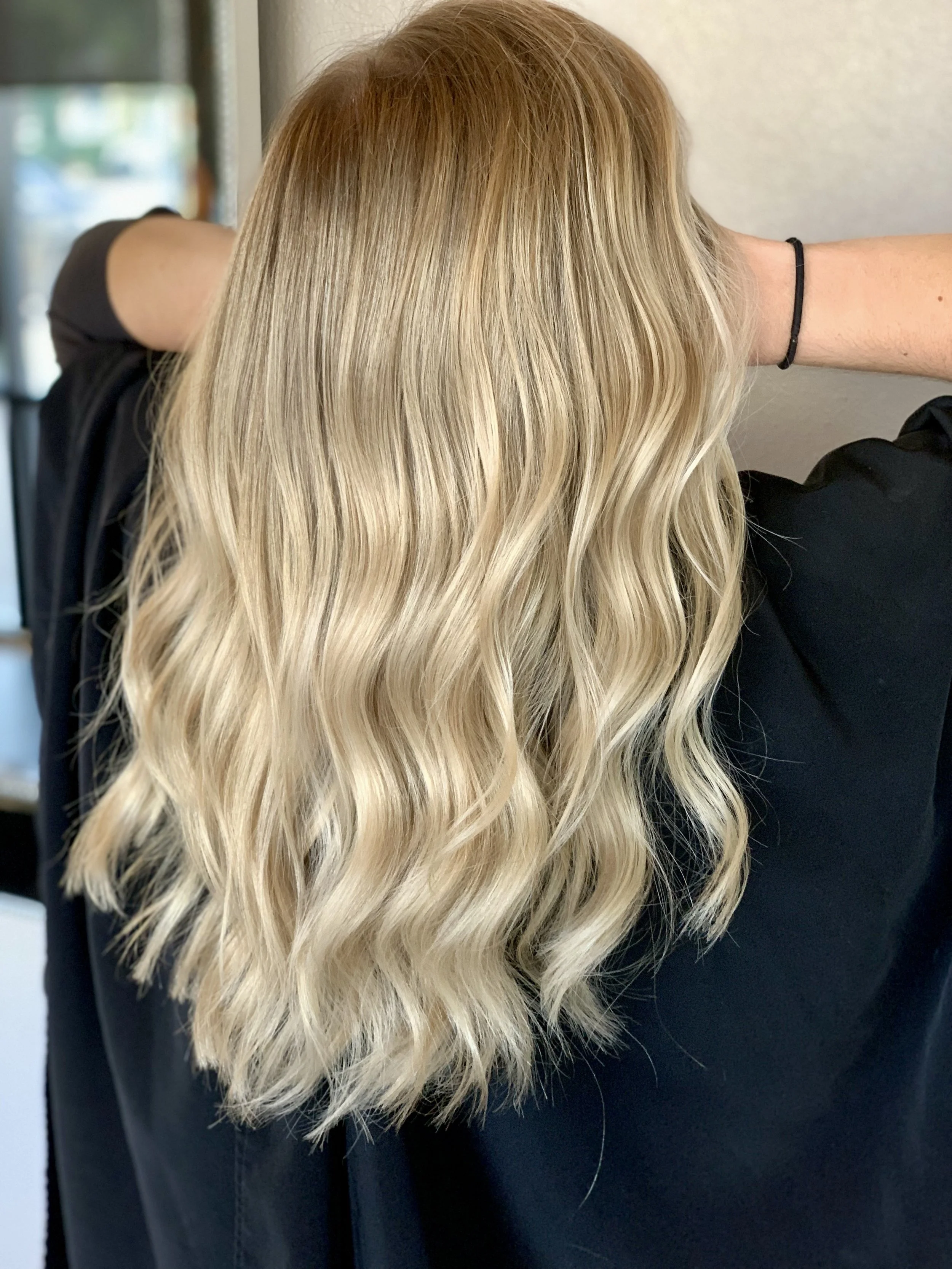Long blonde highlights with soft waves and diffused placement, maintaining neutral tone and natural movement without over-processed or overly bright ends.