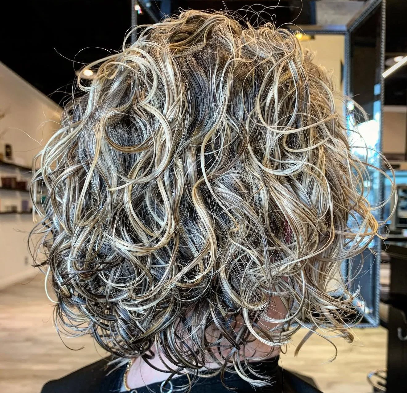 Ouidad curly haircut and dimensional sun-kissed blonde highlights in Nichols Hills OKC by Curly Hair Specialist Scott Risk
