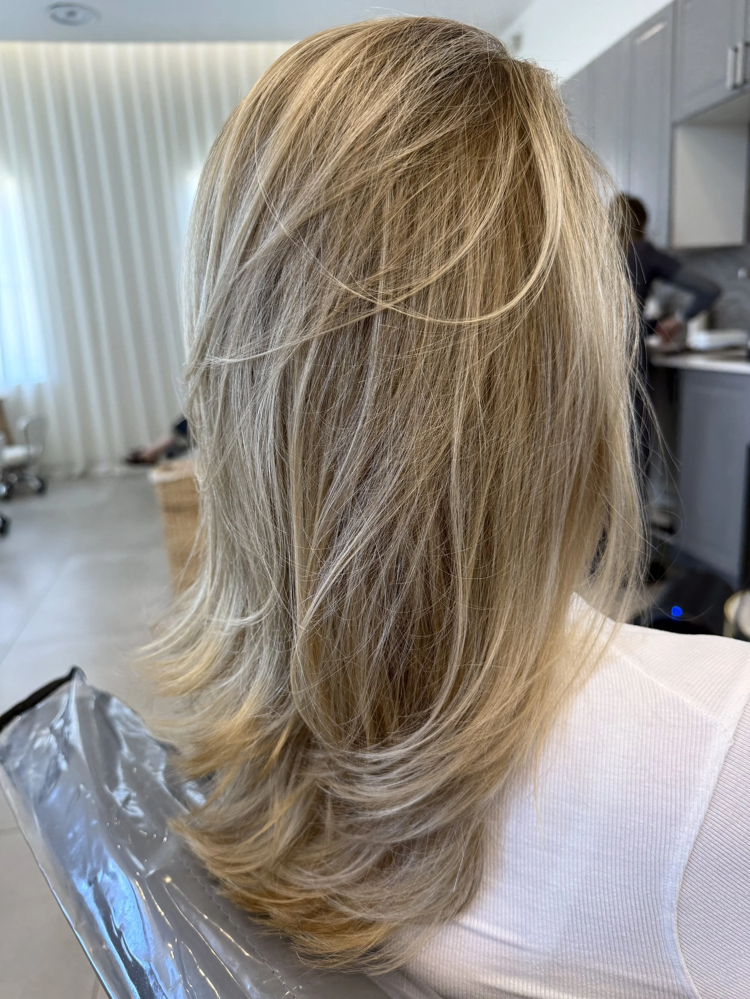 Beige blonde highlights placed with precision to enhance layered movement, delivering balanced dimension and a believable, low-contrast finish.