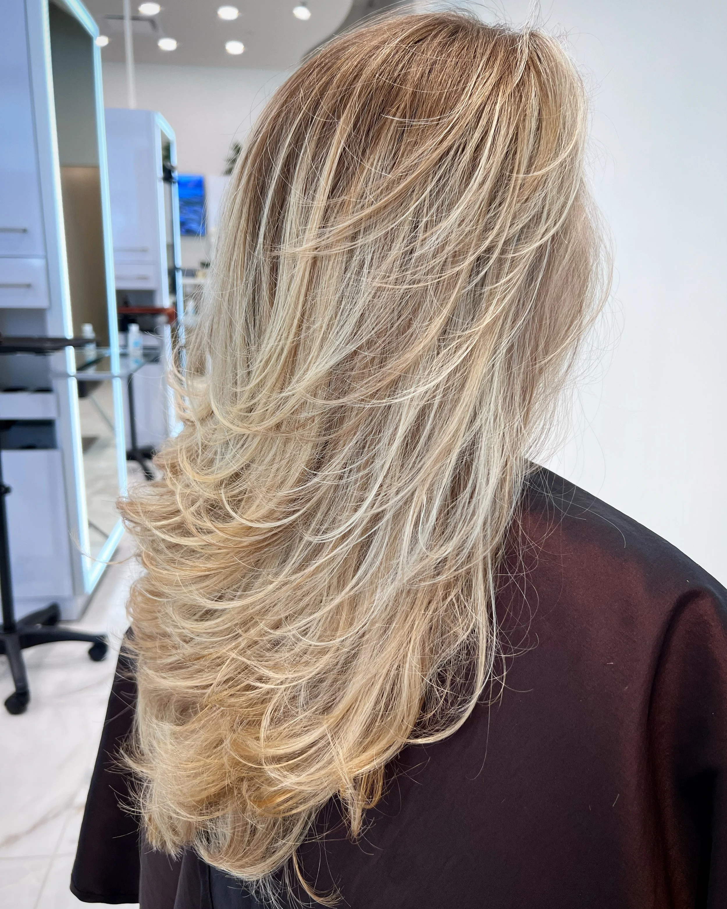 Natural blonde highlights with long layers for soft dimension and clean grow-out in Dallas, Texas.