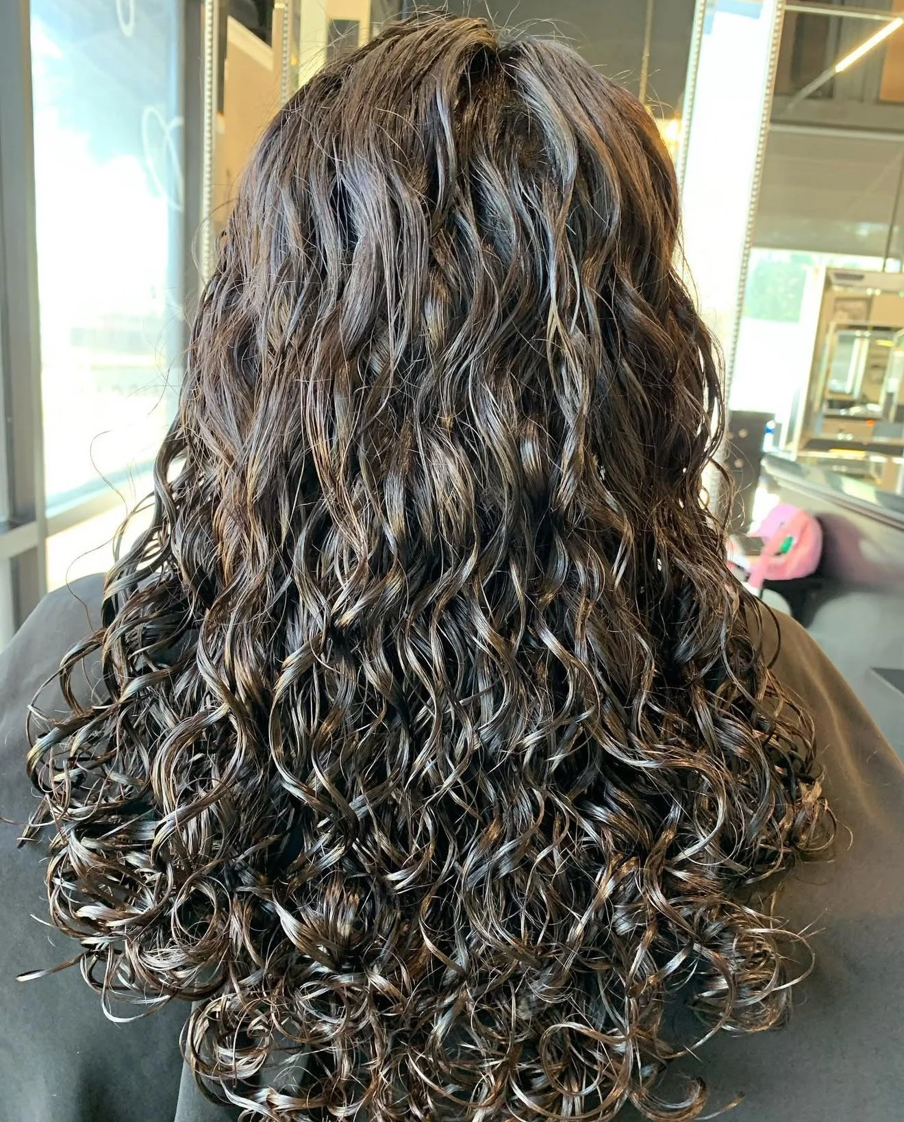 Curly haircut with long defined curls and movement for a soft layered finish