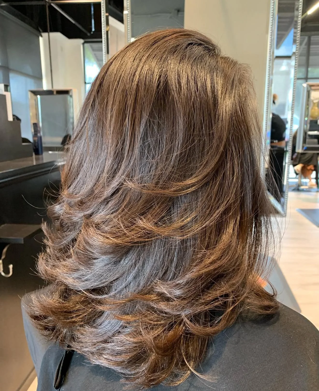 Luxury brunette layered haircut with flowing length and clean architectural layering