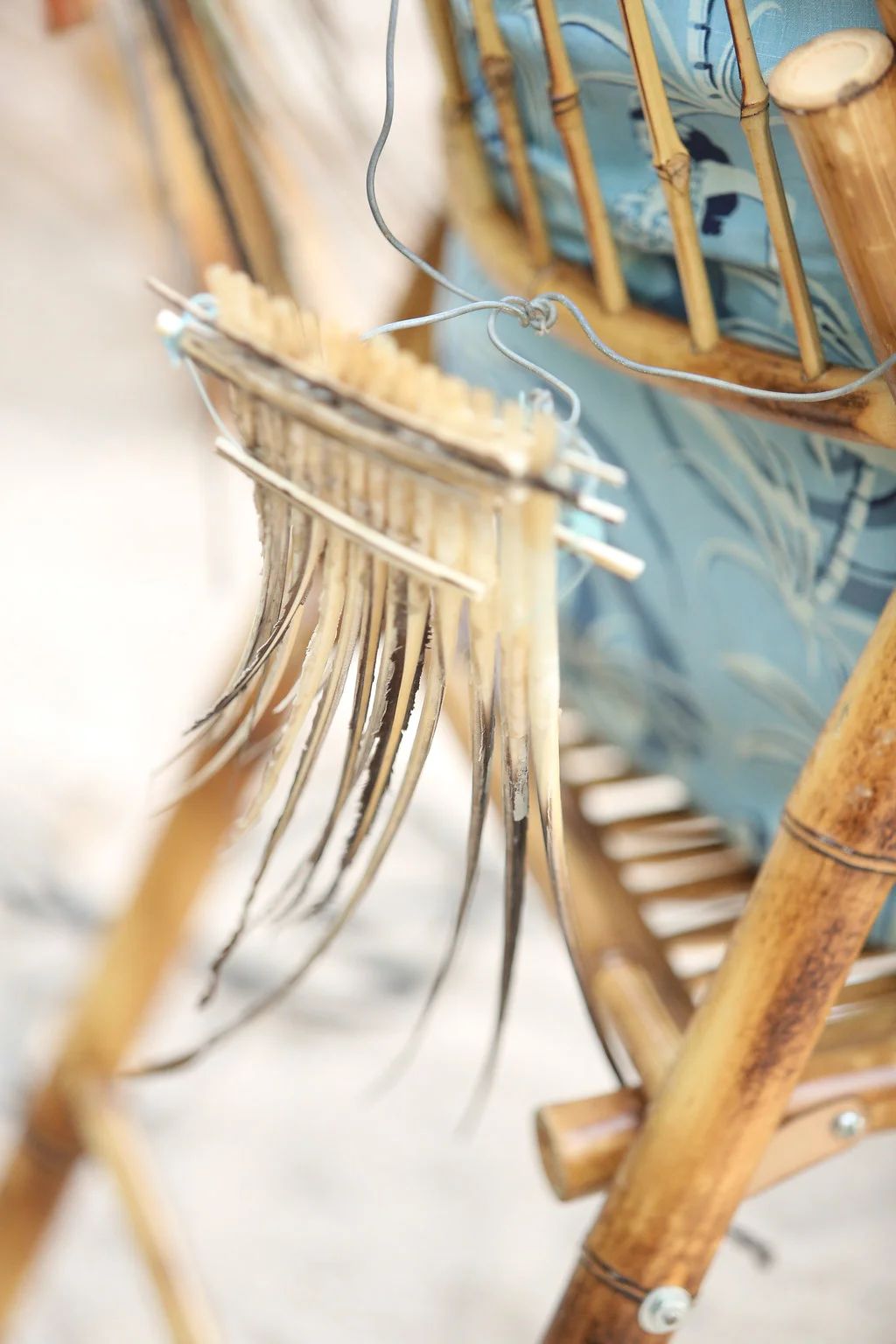Feather accents hang from the back of a bamboo chair during a Costa Rica beach wedding in Santa Teresa
