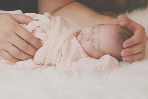 swaddled newborn with daddys hands.jpg
