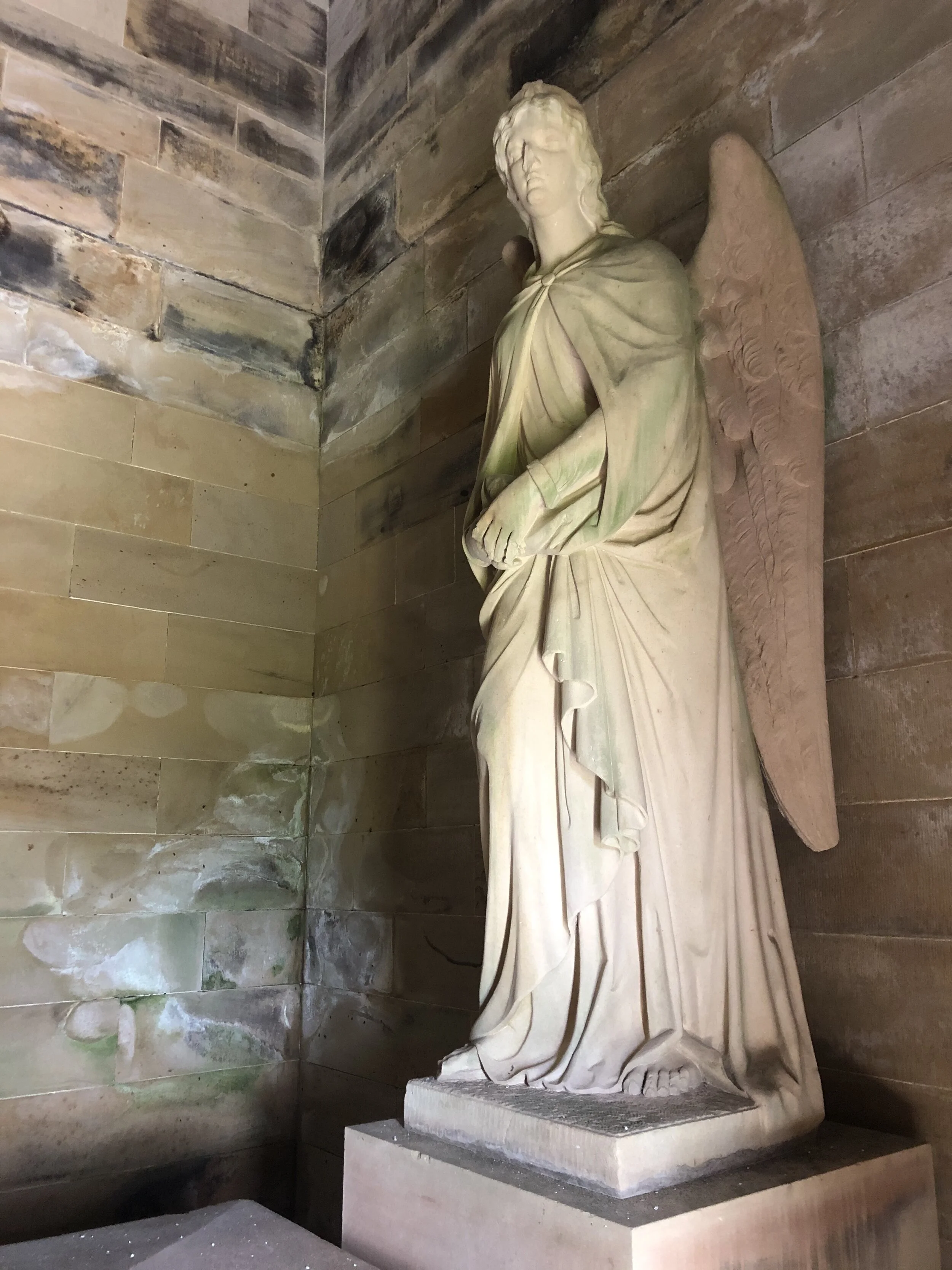 Watching over him: huge stone angels with sandstone wings that must have been lowered into the crypt