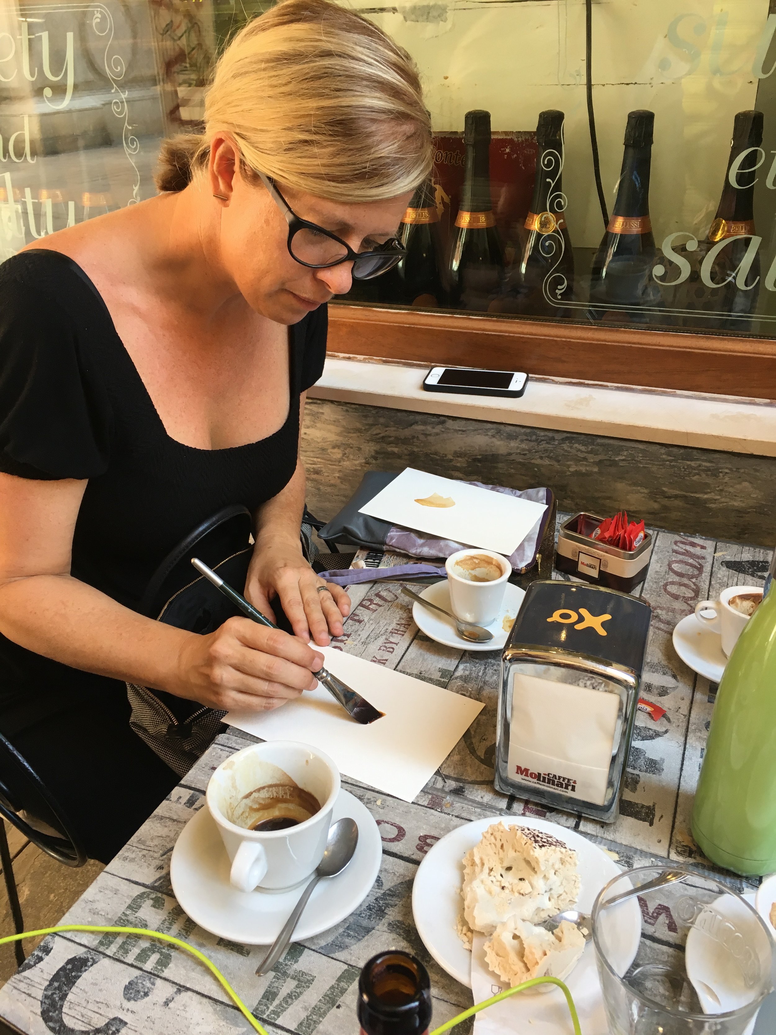 Danielle Krysa painting with coffee in a Venetian café