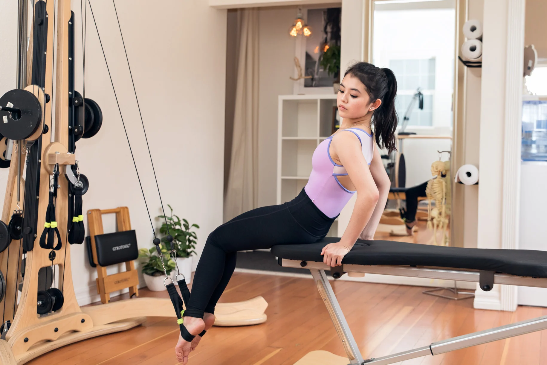 Brand image of the inside of Urban Body San Jose, pictured is a client demonstrating how to use the Gyrotonic.