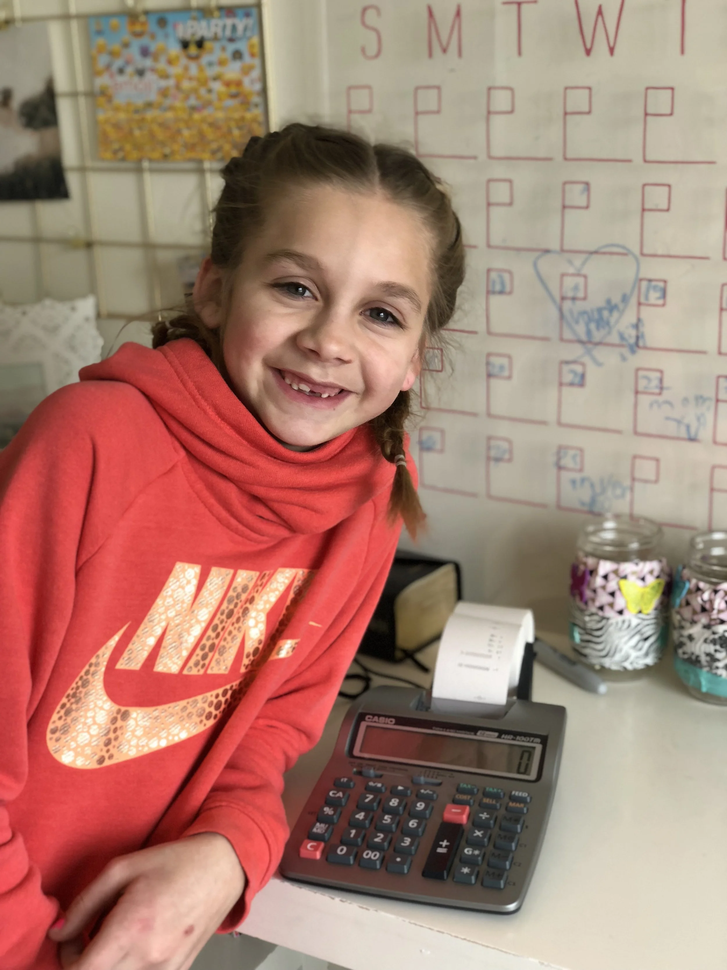 Happy Kolbie posing with the accounting calculator she bought with money from her birthday.