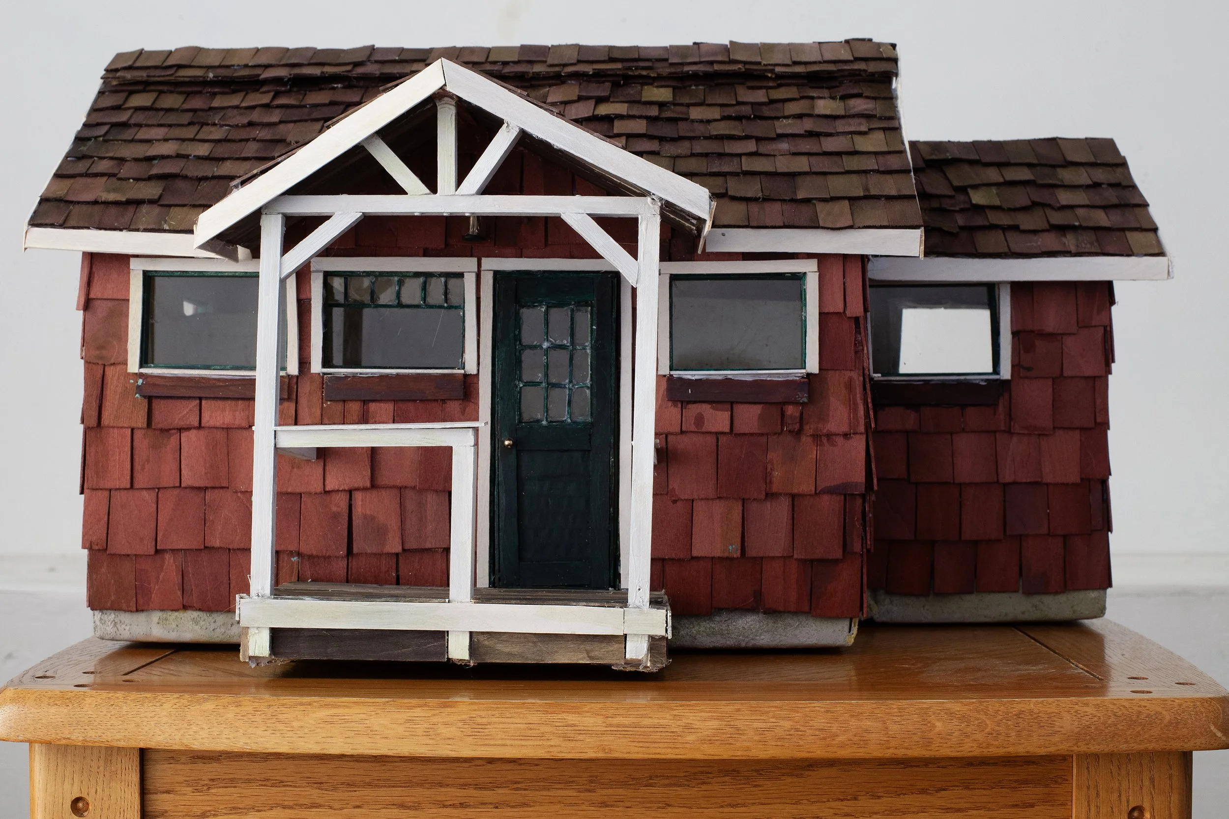   Everyone Is There, Everyone Will Leave at Exactly The Same Time , 2025, cardboard, papier-mâché, wood, dye, acrylic paint, glass, wire, lemongrass, coffee, cloves, audio loop featuring loved ones (living and dead), flameless candles, table, 24 × 14