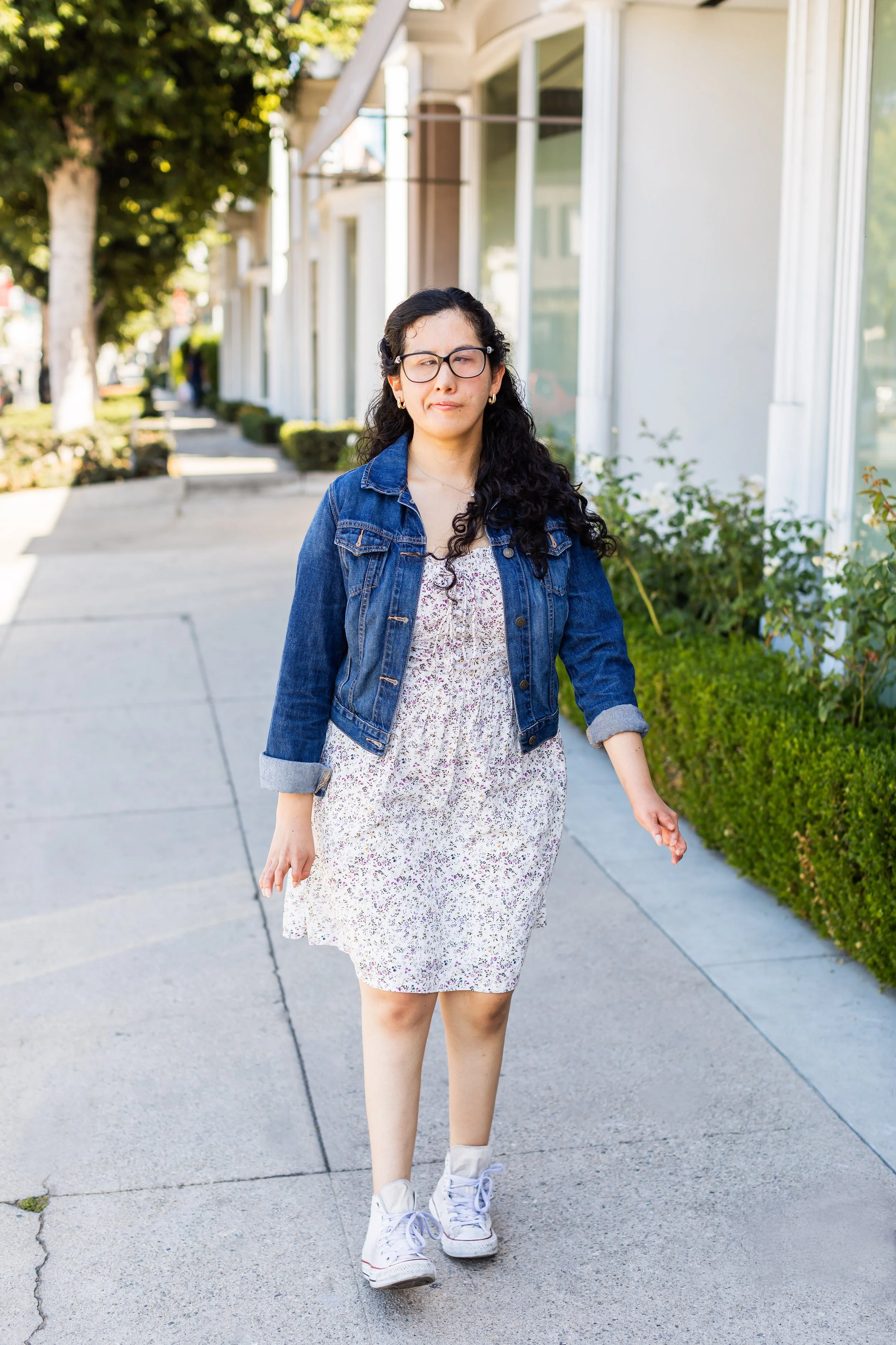 A woman walks down a sidewalk during her personal branding portrait session for her work as a creative illustrator. 