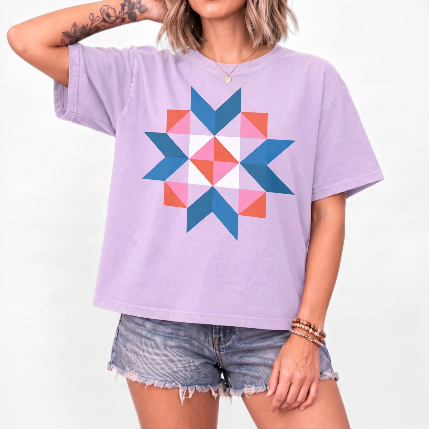Woman wearing the Sunday Social quilt block boxy t-shirt by She Makes Joy in Orchid, a Comfort Colors boxy tee with a blue, coral, and pink star block