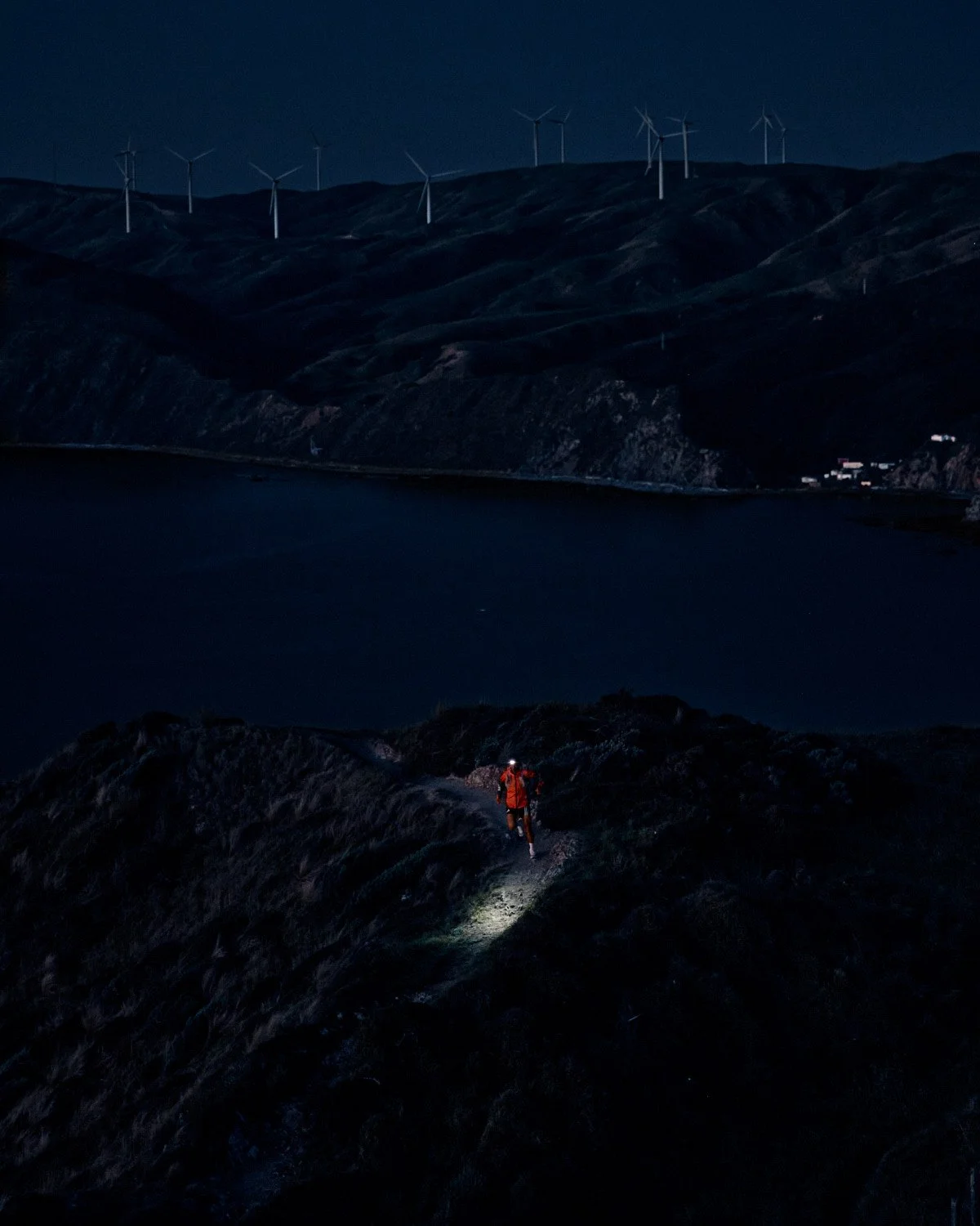 Trail runner Dan Jones running near wind turbines at night, athlete photography for Fenix