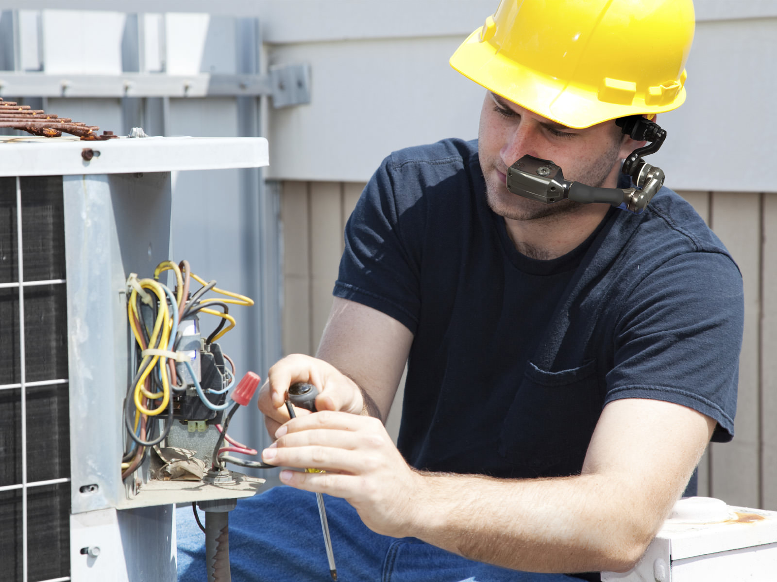 A hard hat wearing electrical engineer wearing HC1 while examining a bundle of wiring