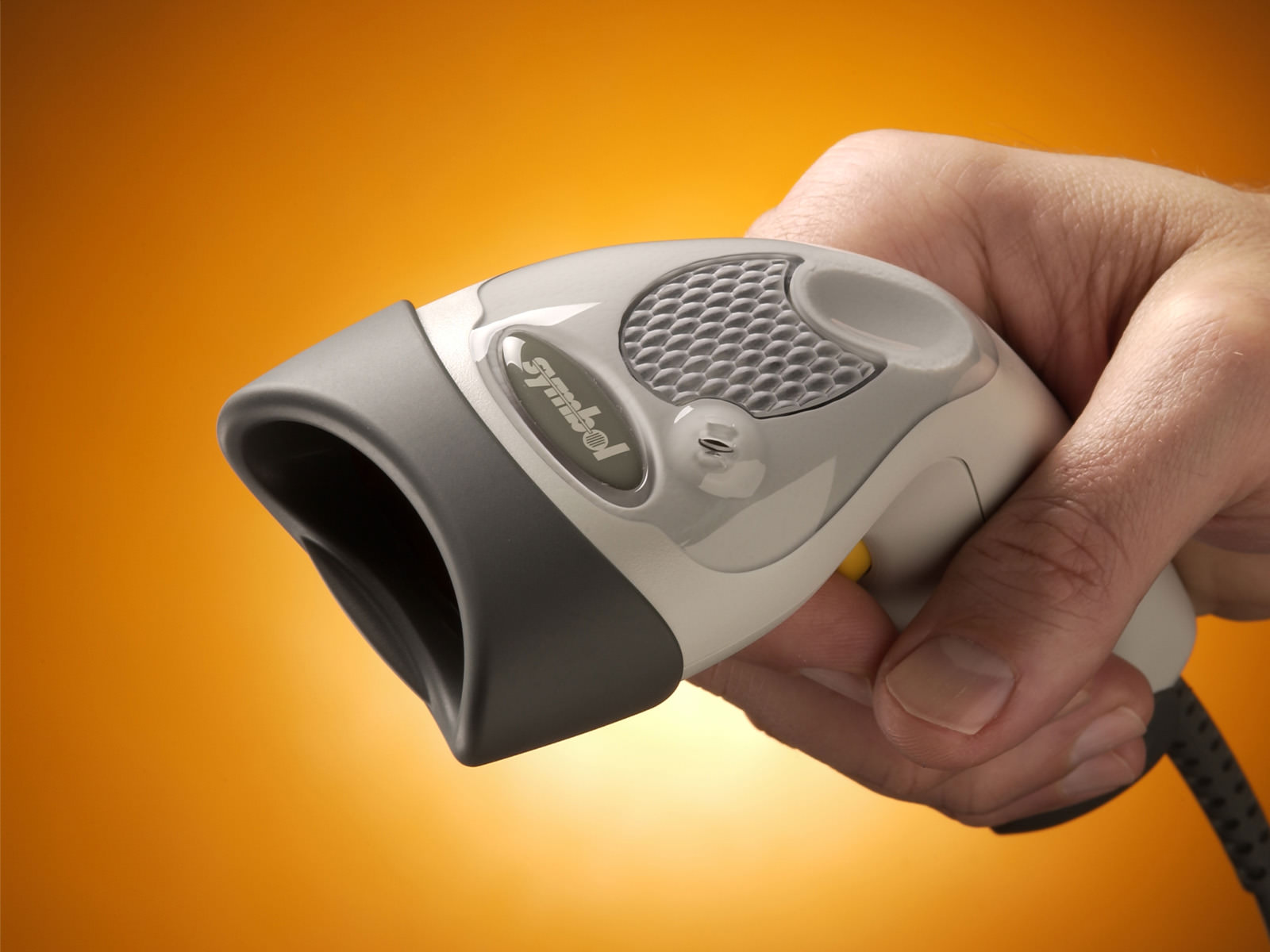 Top view of a hand holding the LS1908 with the lightpipe against a gradient yellow-orange background