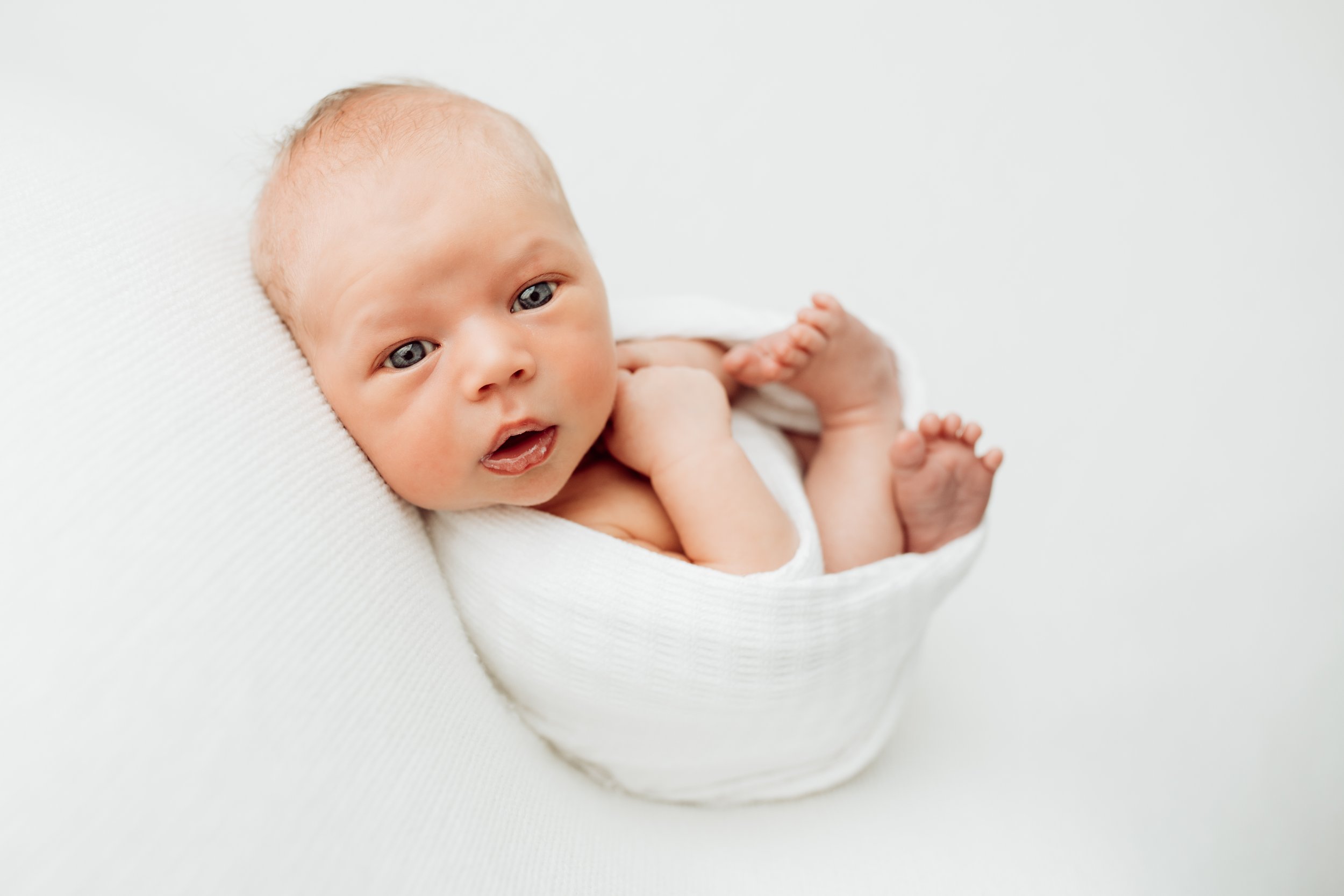 Newborn baby with blue eyes looking at camera