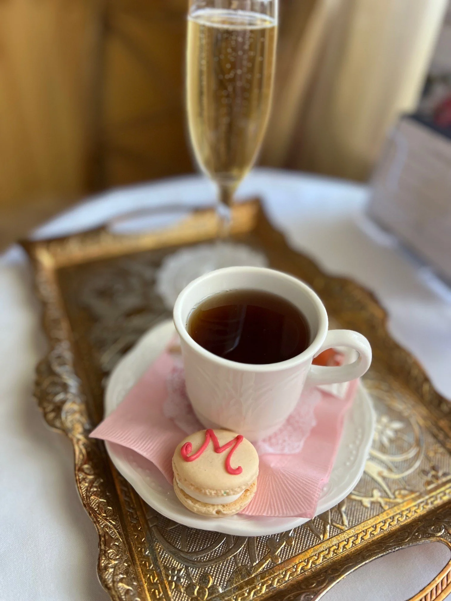 hot tea and a madonna inn macaroon served on a gold tray
