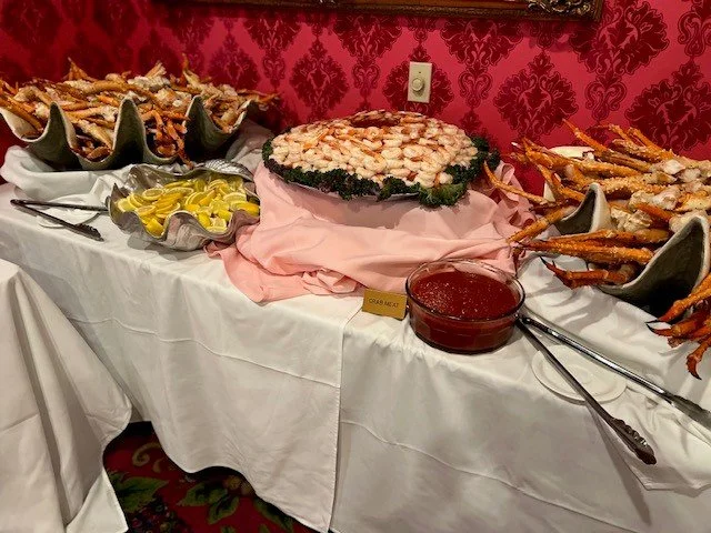 cold king crab legs, shrimp, lemon, and cocktail sauce against a red velvet wall