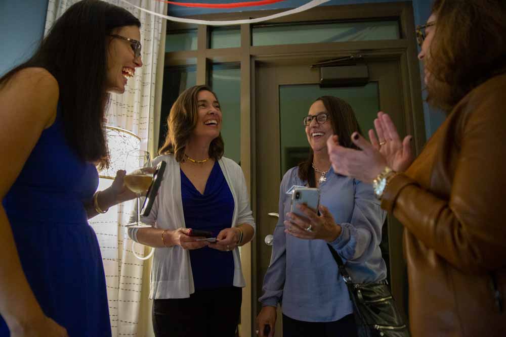  Anita Earls, Brenda Richardson, and Caroline Spencer, Anita’s campaign manager, laugh at a photo on Richardson’s phone of a nearby polling place in Durham. A sign at the location says, “They don’t want us to vote for Anita Earls.” 